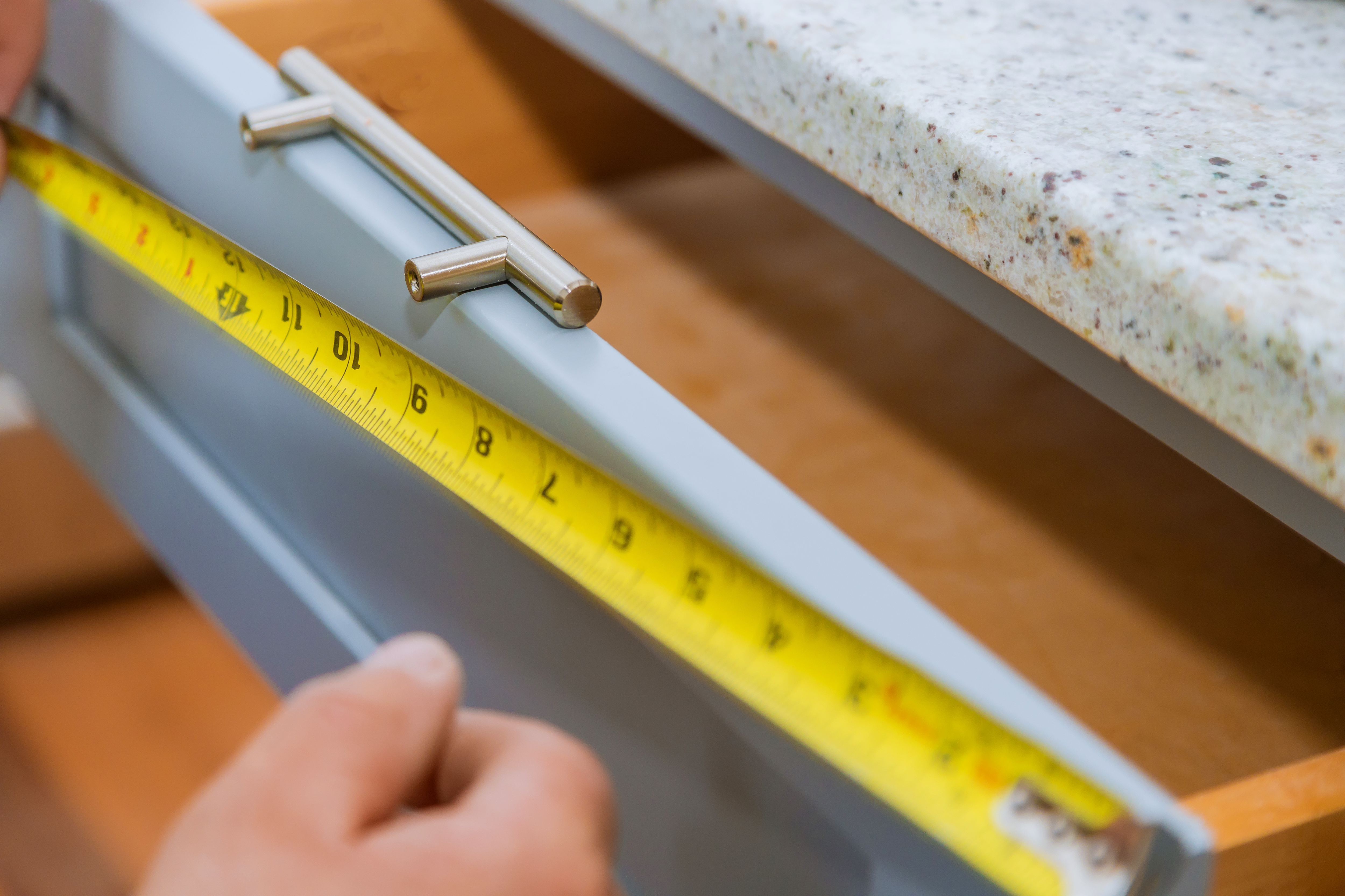 Installation of measuring drawers handles on kitchen cabinets